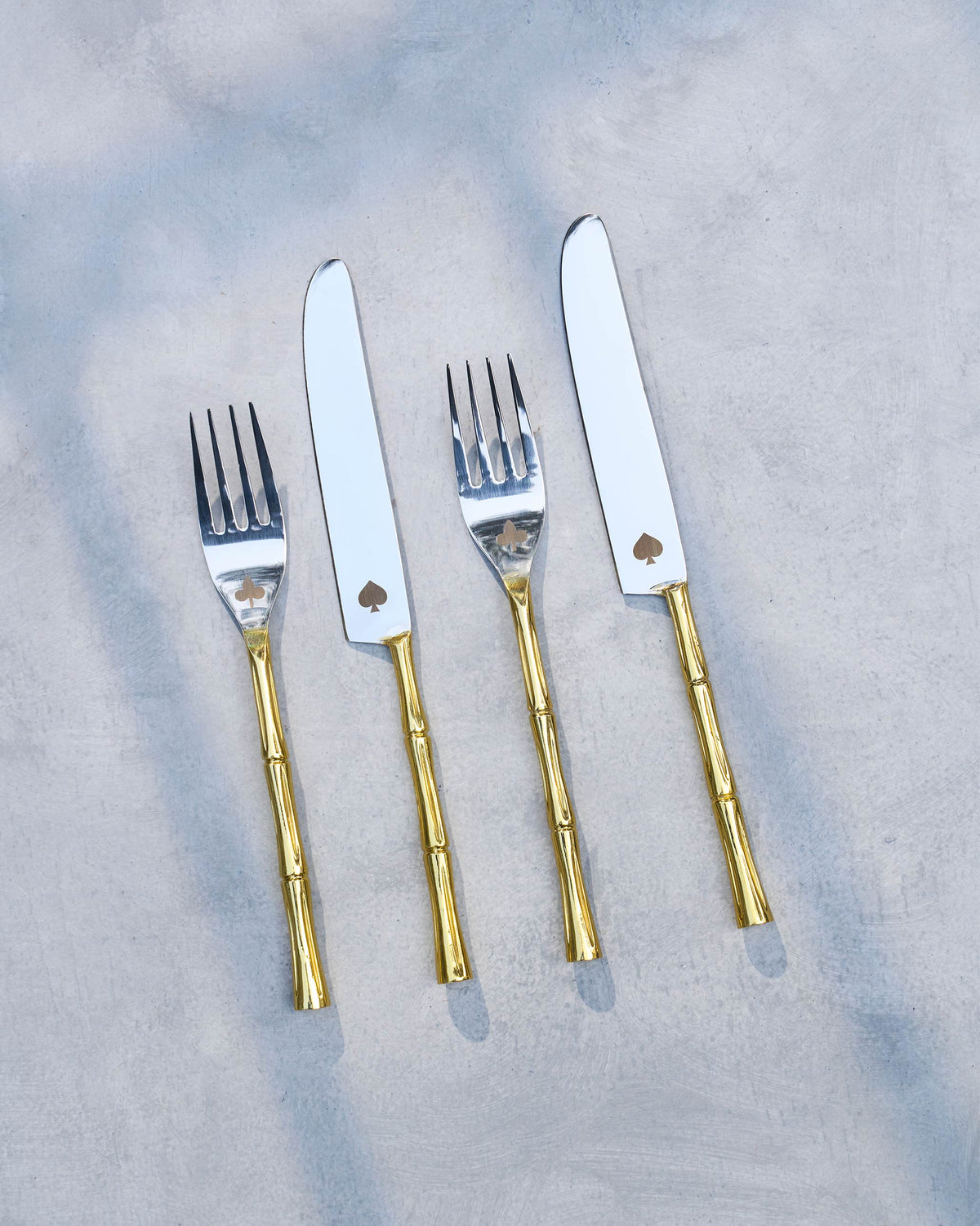 Spade & Club cutlery set of four laid flat, with spade cut-outs on the blades.