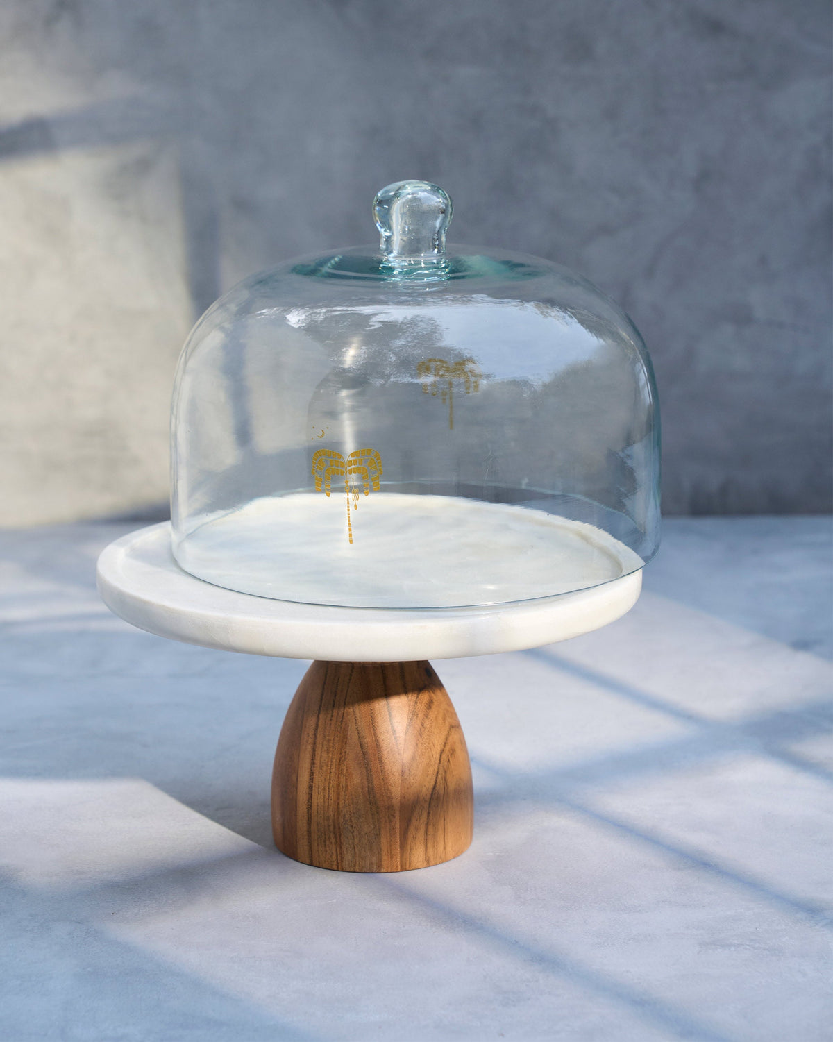 Safari Cloche with its dome set on the marble stand and wooden base.