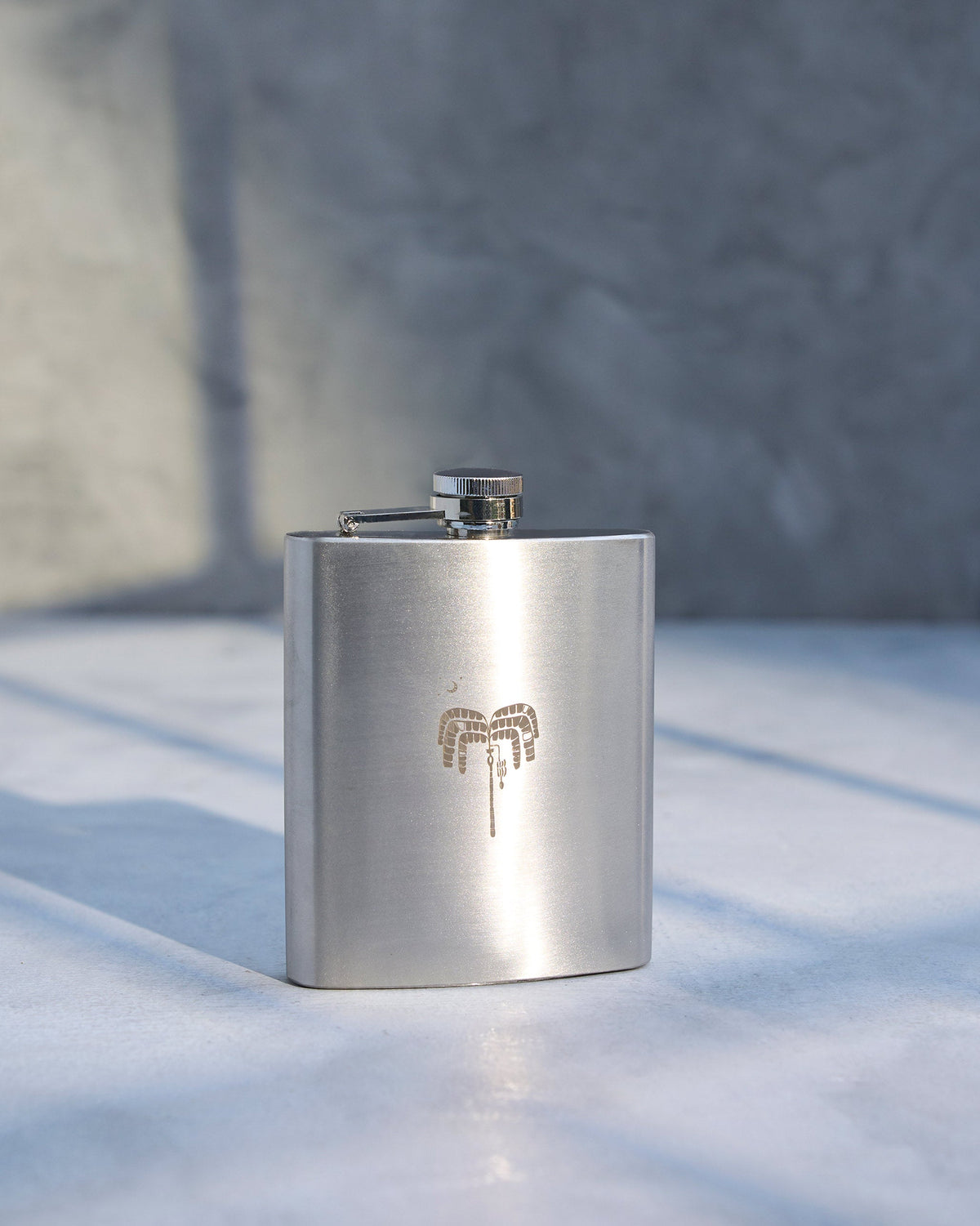 Safari Flask standing upright on a light surface, with an engraved motif.