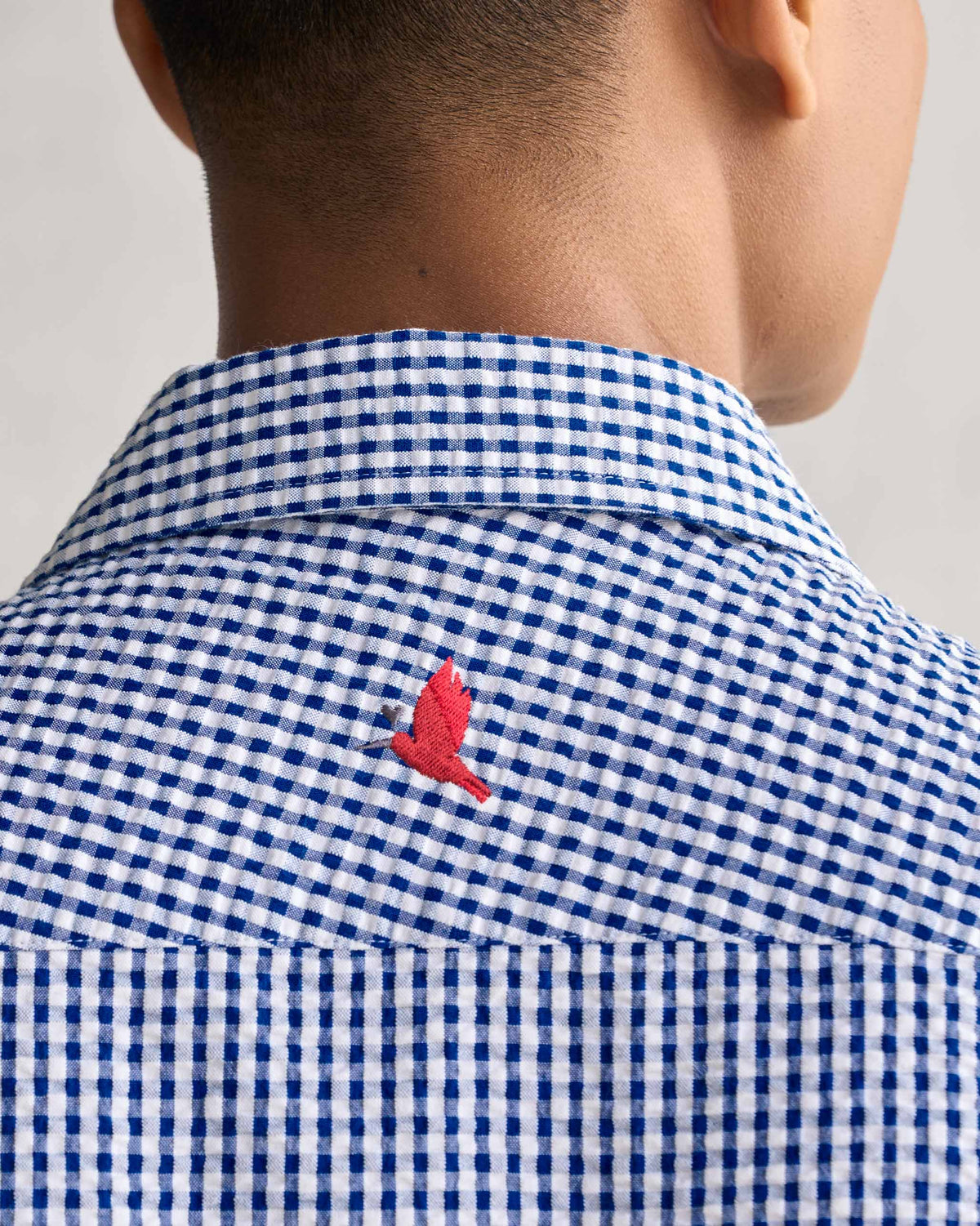 Close-up of the Holiday Shirt's back collar showing a small red bird embroidery.