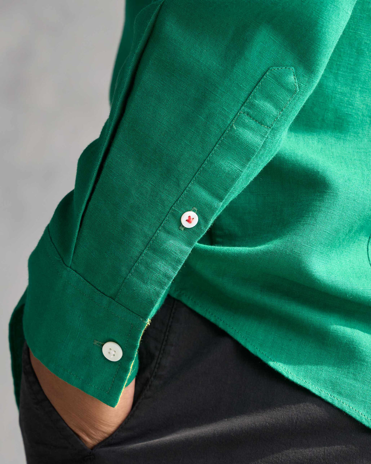 Close-up of a rolled sleeve on the green Captain shirt with a white and red button.