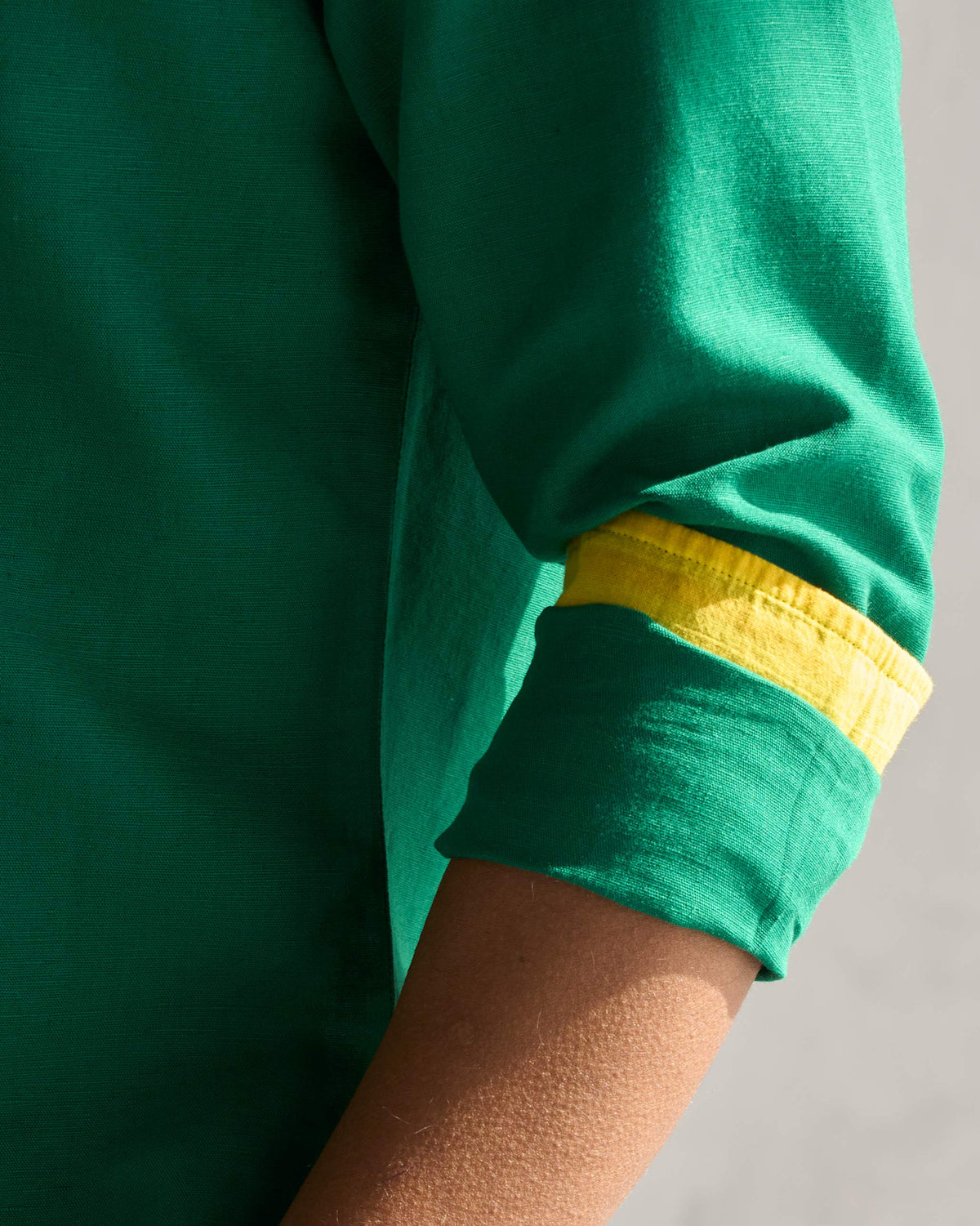 Close-up of the green Captain shirt sleeve, rolled to show a yellow cuff lining.