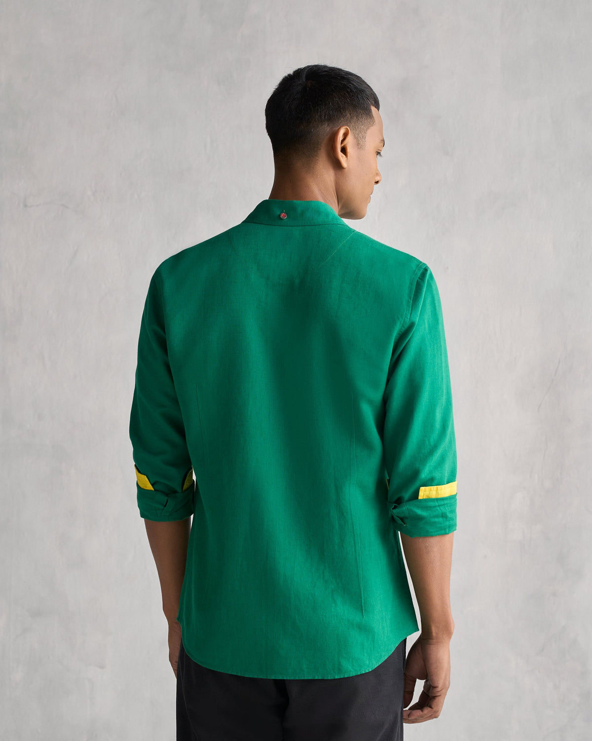 Back of the green Captain shirt worn by a person, with yellow cuff linings.