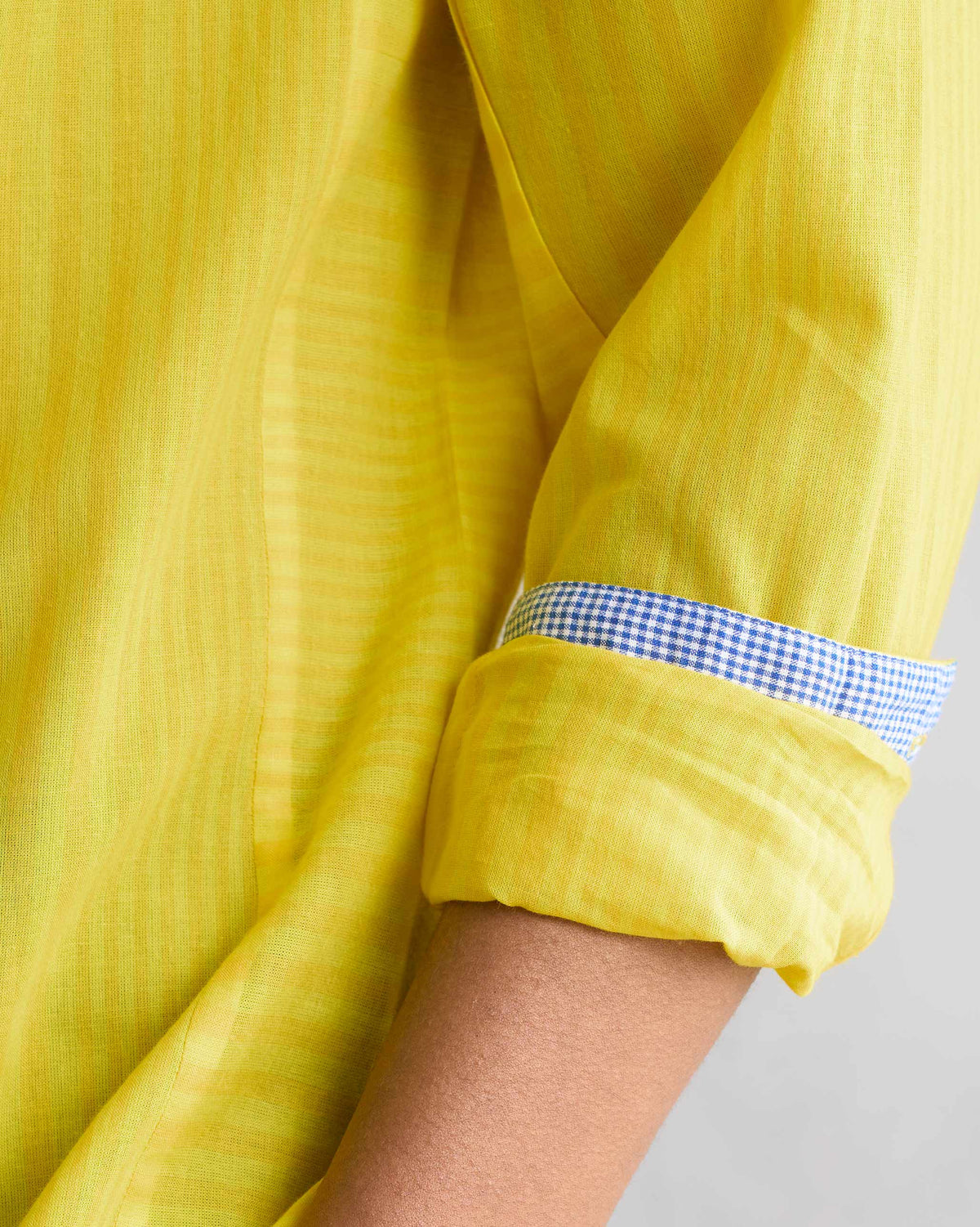 Close-up of a yellow Side Placket shirt cuff showing a blue and white gingham lining.