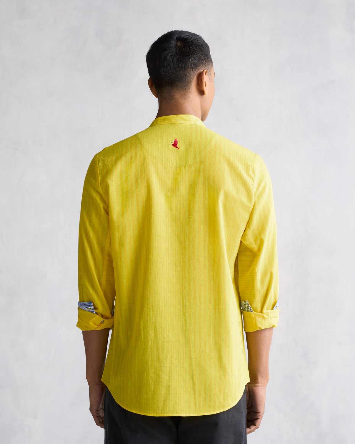 Back of a yellow Side Placket shirt with a small red bird embroidery worn by a person.