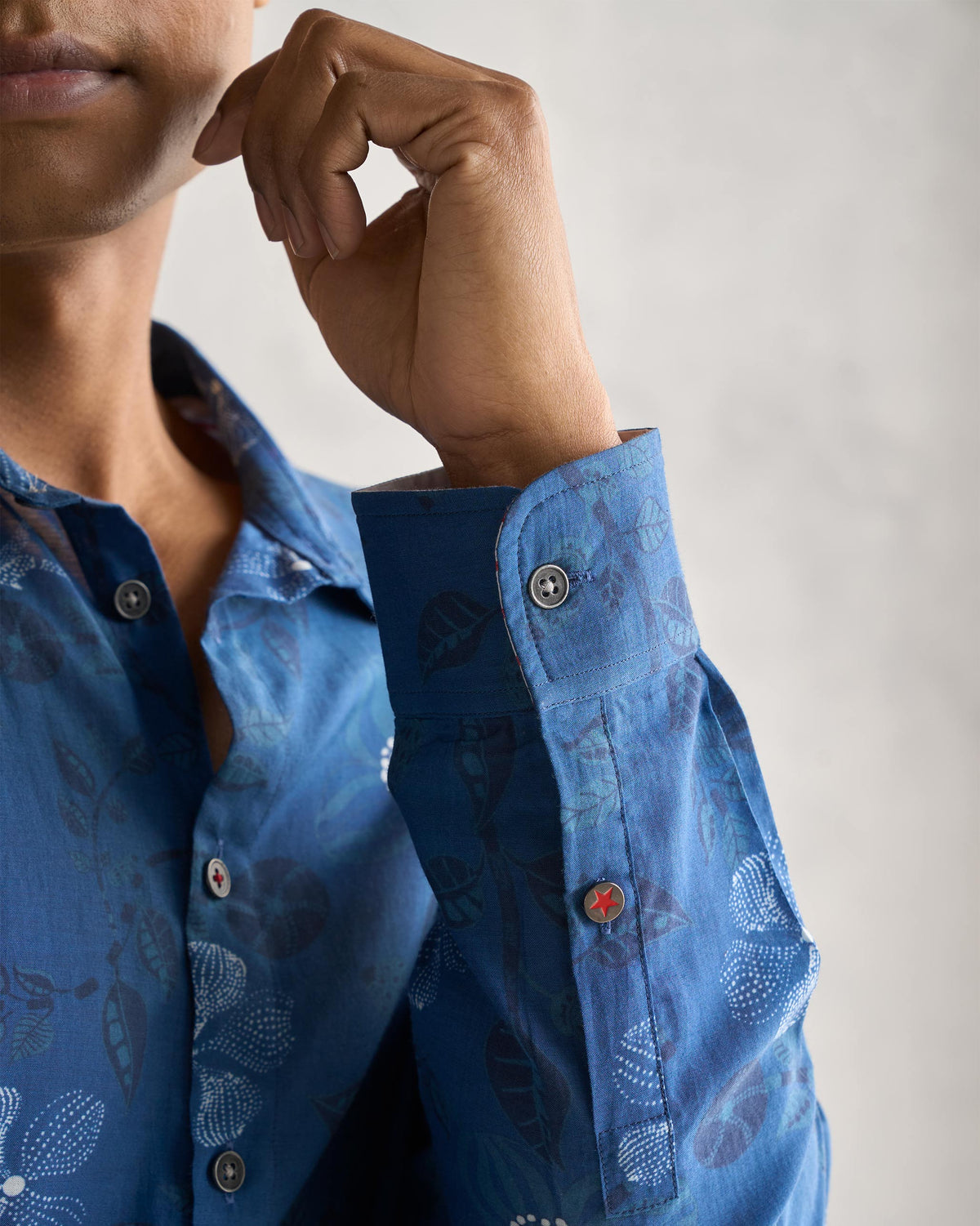Close-up of a navy Hakuna Shirt cuff with a red star button.