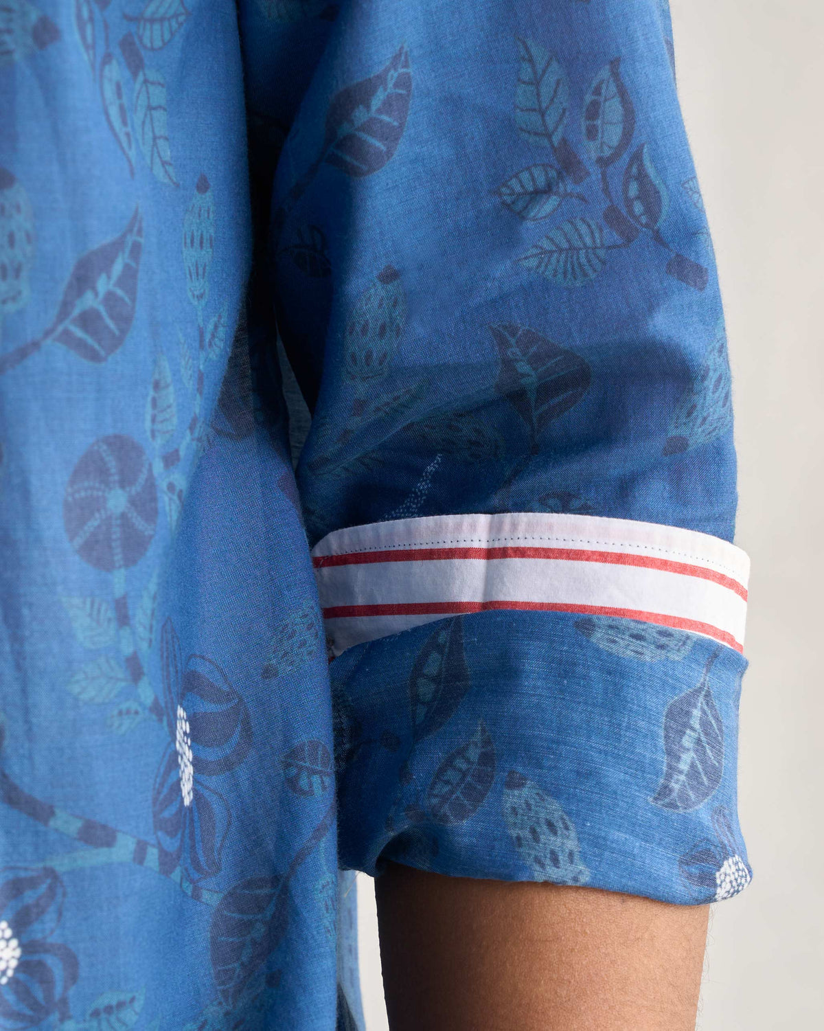 Close-up of a navy Hakuna Shirt sleeve with a white and red striped cuff.