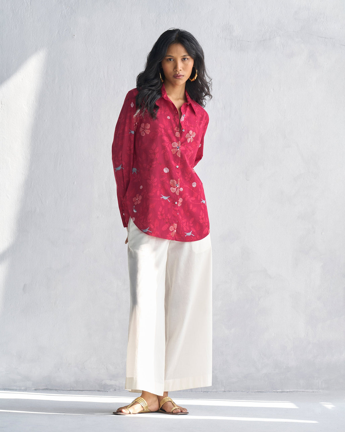 Person wearing a red Tropico Shirt with a floral print, shown full length.