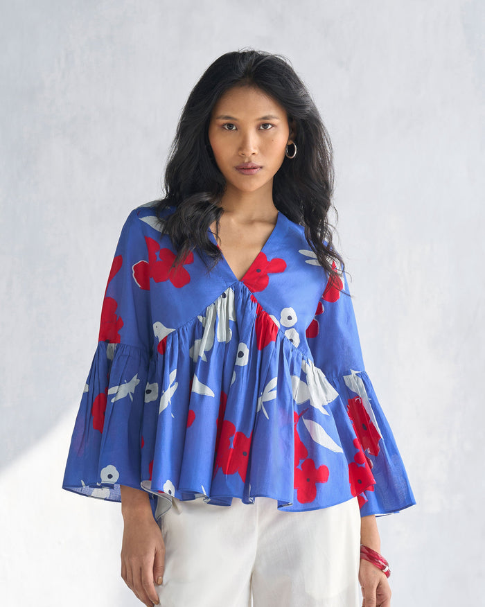 Person wearing a blue Ruffle Top with a red and white floral print and bell sleeves.