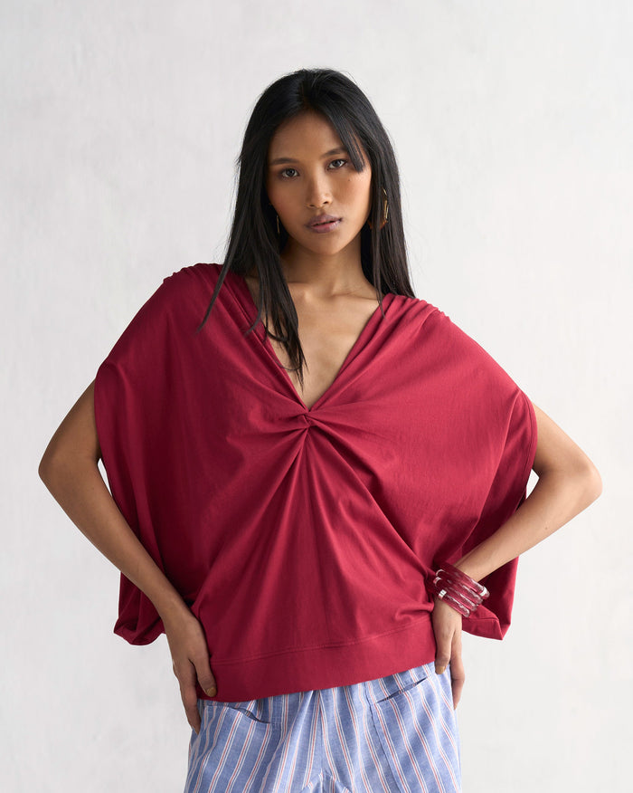 Person wearing a red Adah Top with a gathered V-neckline and wide sleeves.