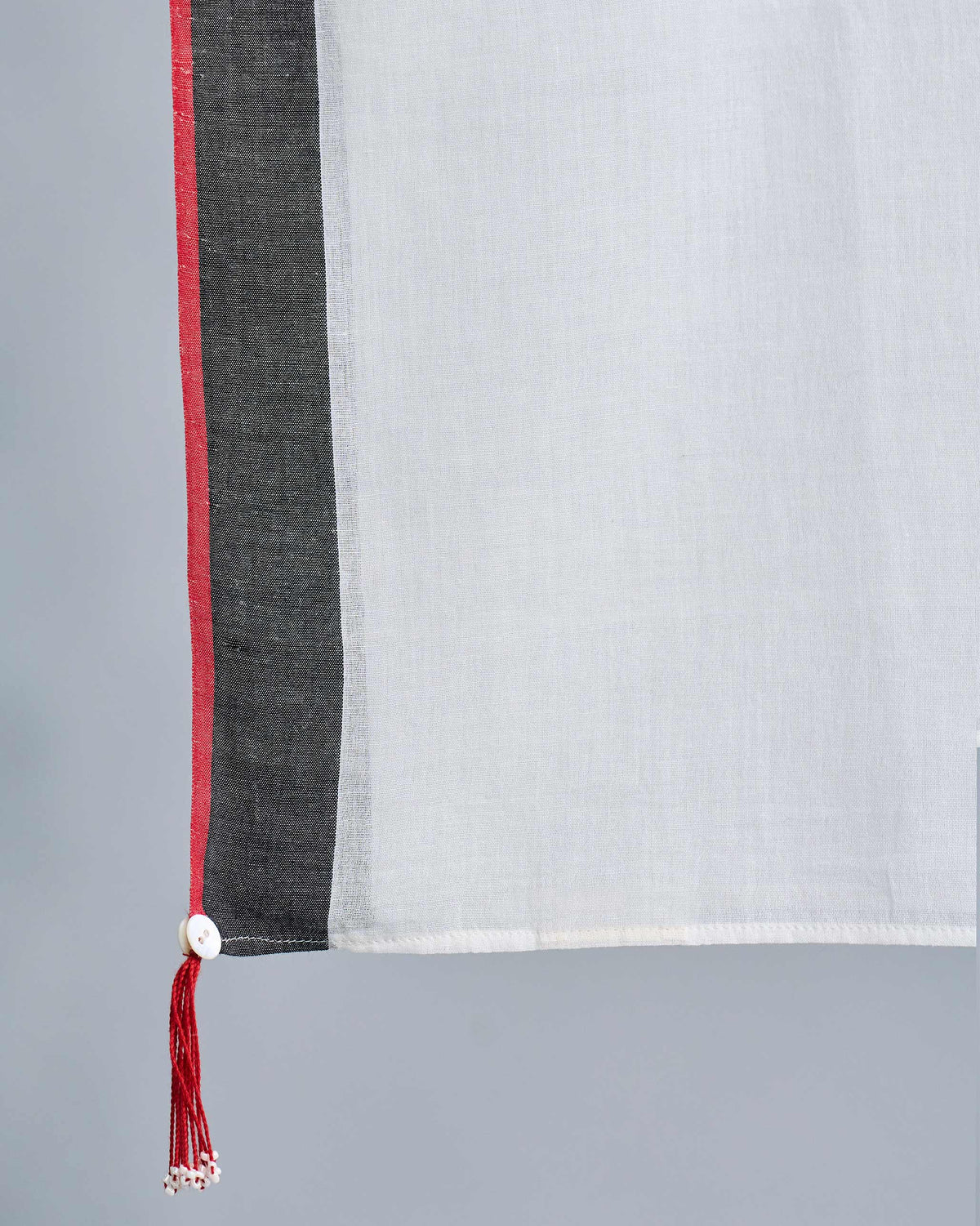 Close-up of an ivory Jalsa Scarf corner with a red tassel.
