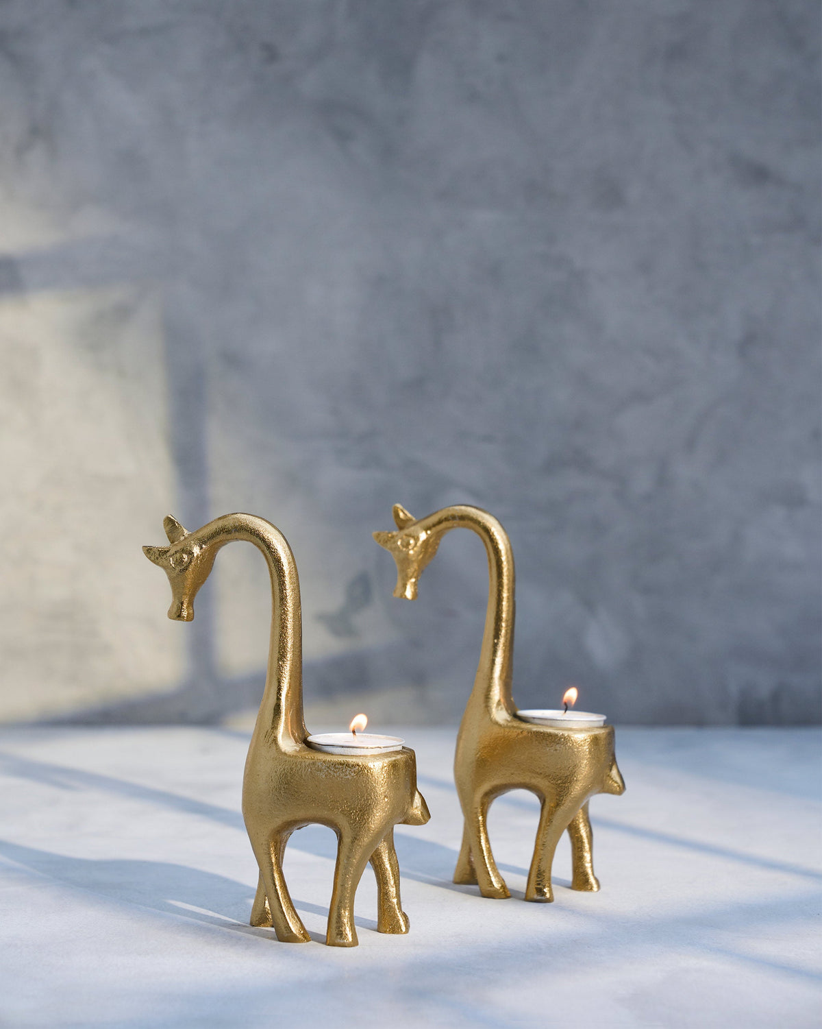 Giraffe Tealight Holders standing side by side, each holding a lit tealight.
