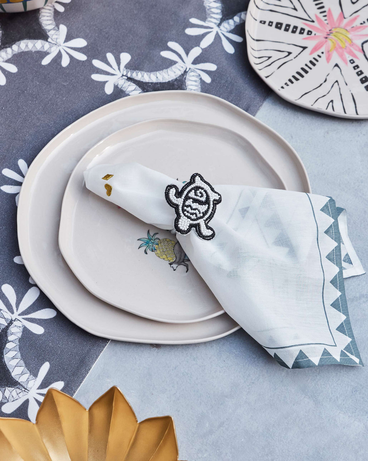 Tinga Napkin Ring with a beaded motif, holding a folded white napkin on a plate.