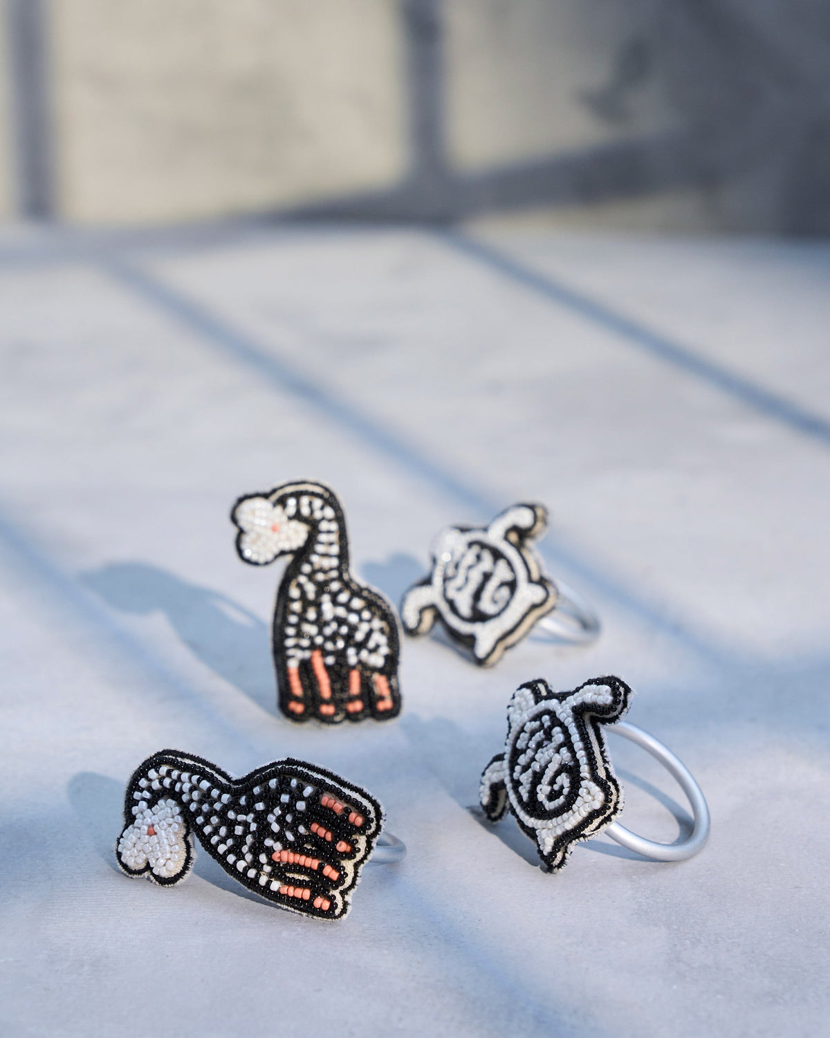 Four Tinga Napkin Rings from a raised angle, with black beaded motifs.