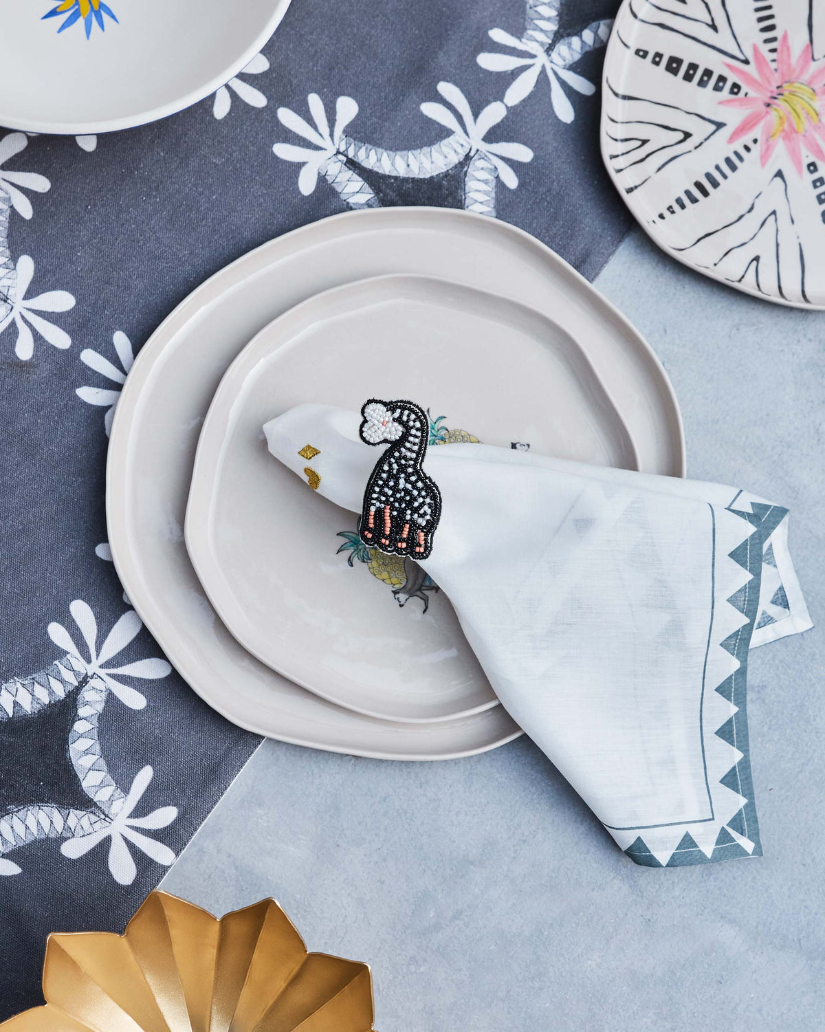Tinga Napkin Ring with a long-necked motif, slotted into a folded napkin.