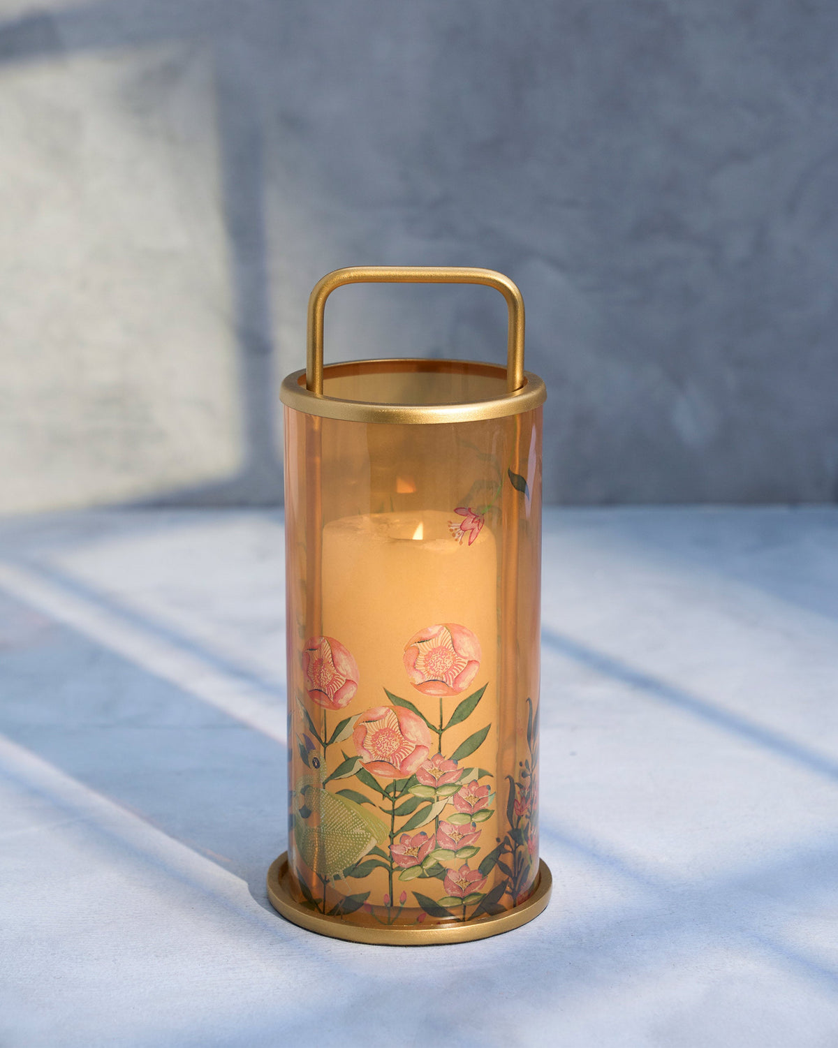 Flamingo Lantern with a lit candle inside, showing pink printed flowers.