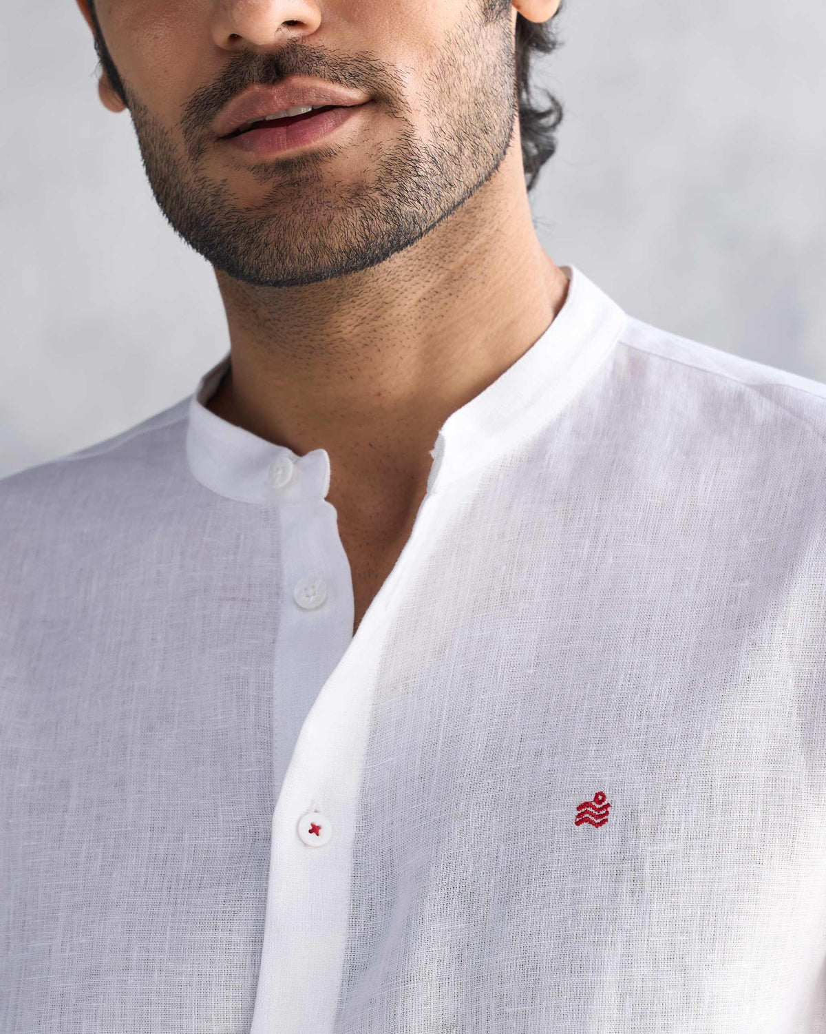 Close-up of a white Nawab shirt showing the Nehru collar and red logomark.