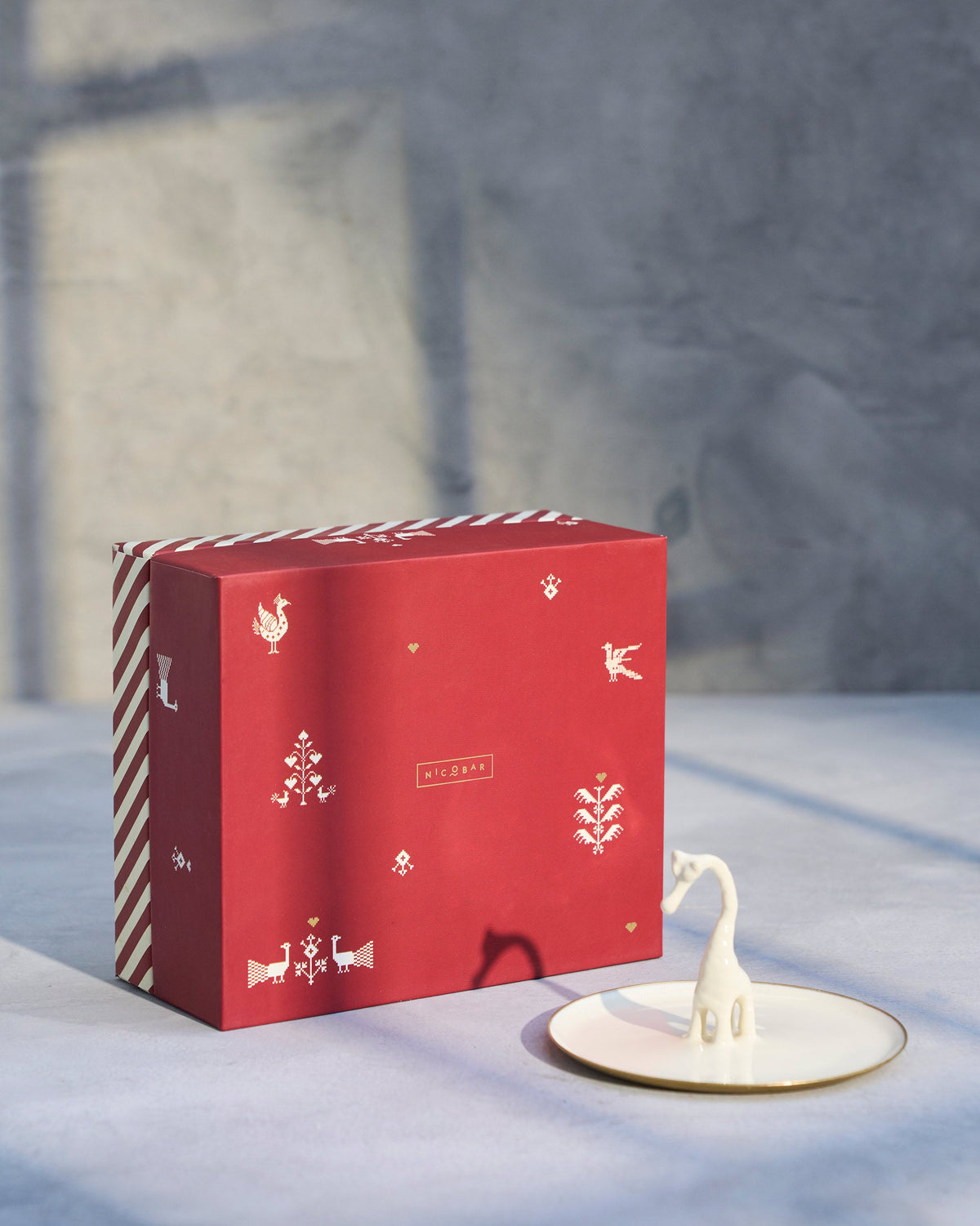 Giraffe Trinket Tray beside a red Nicobar gift box.