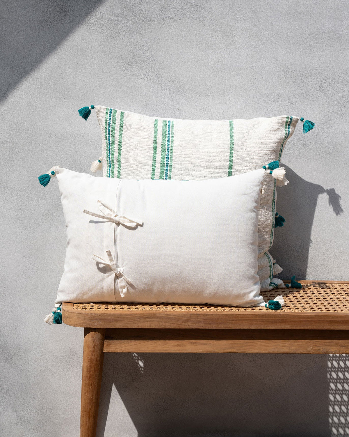 Plain white cushion with tie details on a wooden bench.
