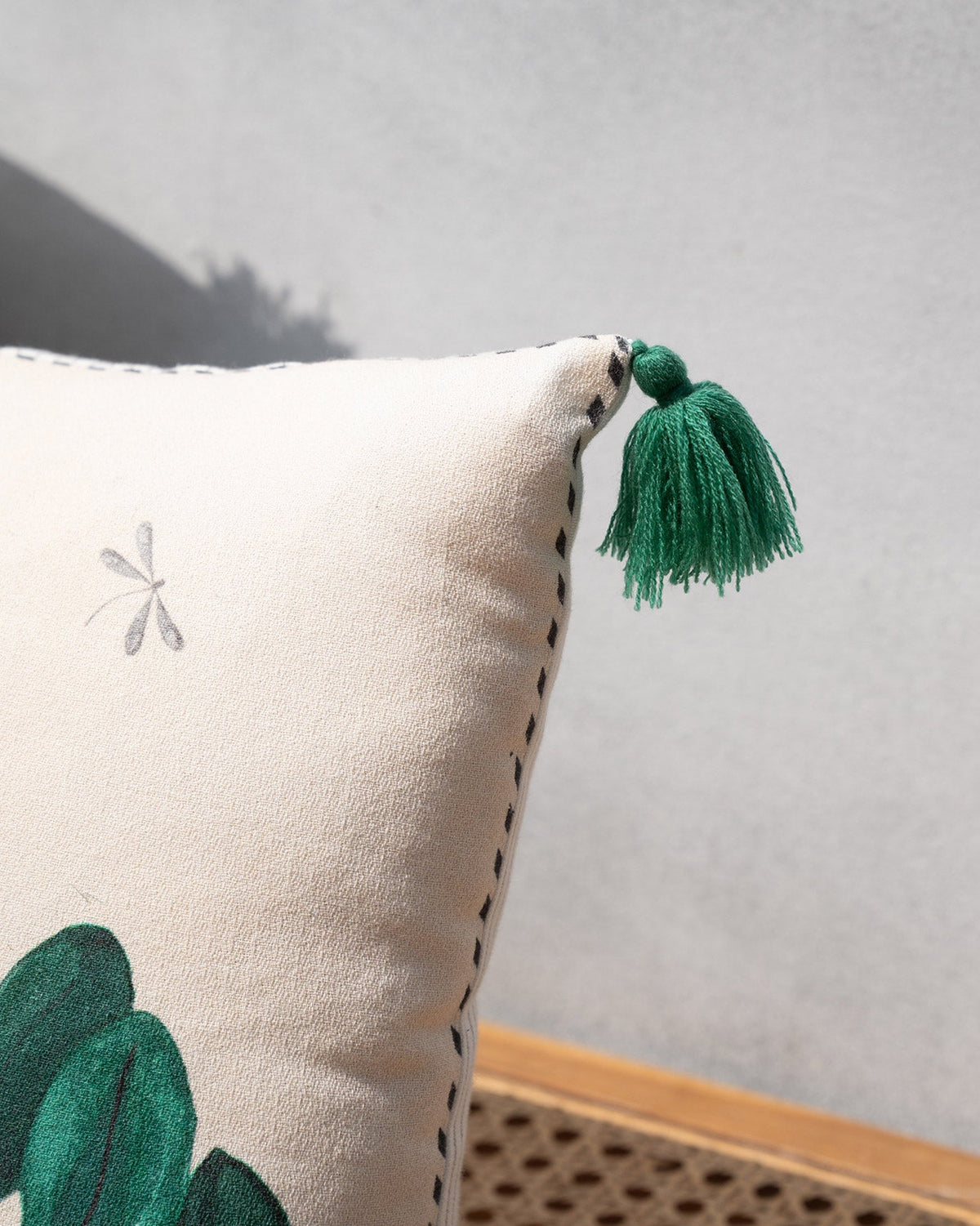 Close-up of a Clove Lumbar Cushion Cover corner showing its green tassel and stitched edge.