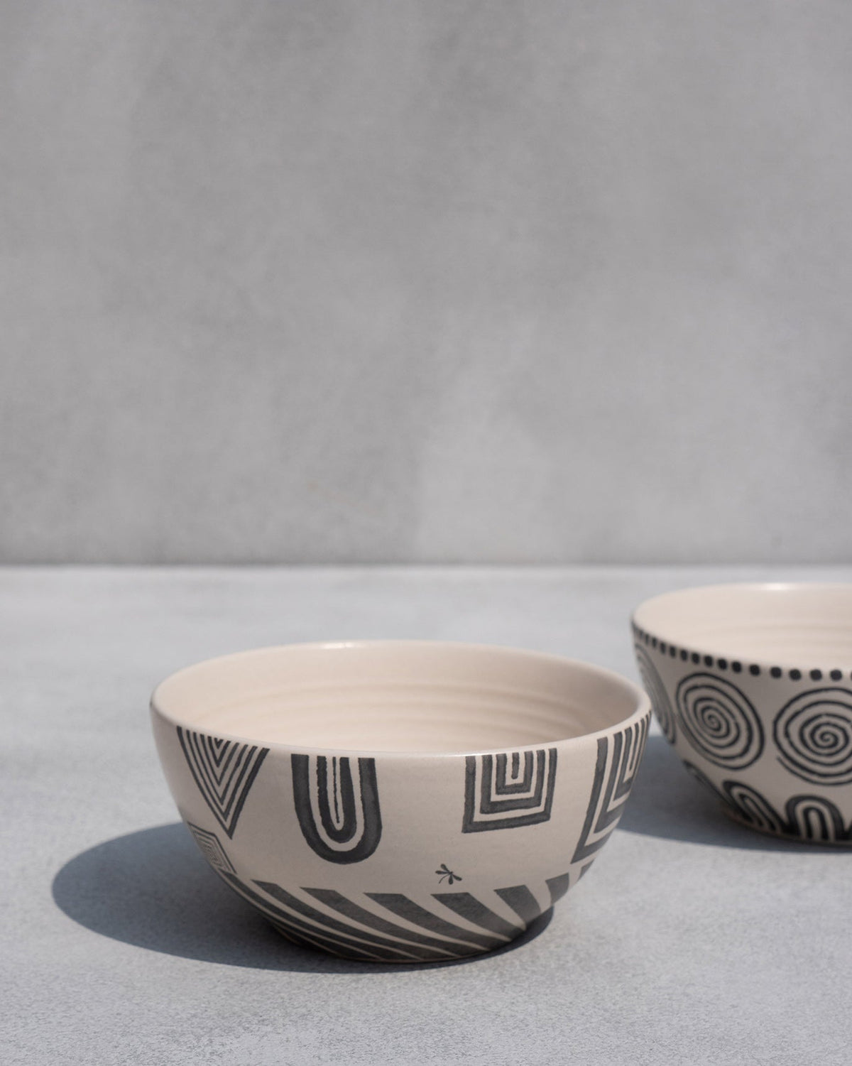 Serenity cereal bowl with a geometric pattern, next to a spiral-patterned bowl.