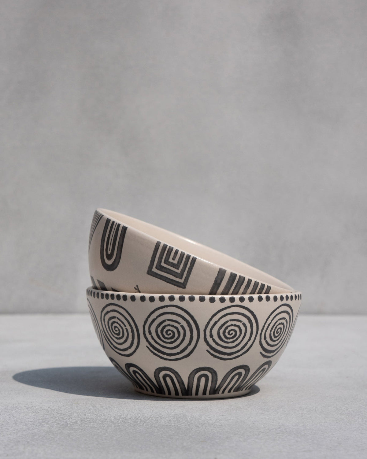 Serenity cereal bowls stacked, the lower one with spiral and arch motifs.