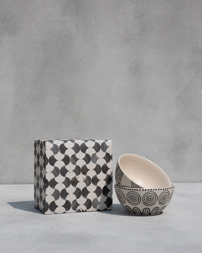 Serenity cereal bowls stacked beside a black and white patterned box.