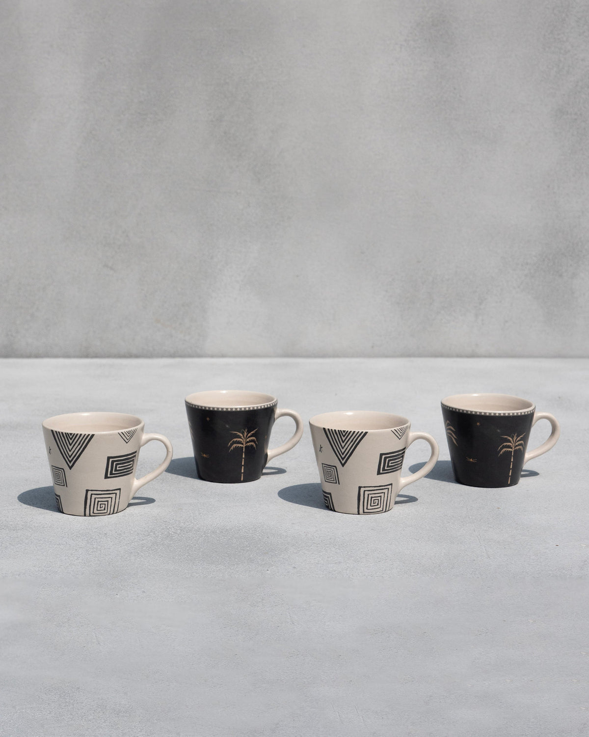 Row of four Serenity espresso mugs in geometric and palm prints.