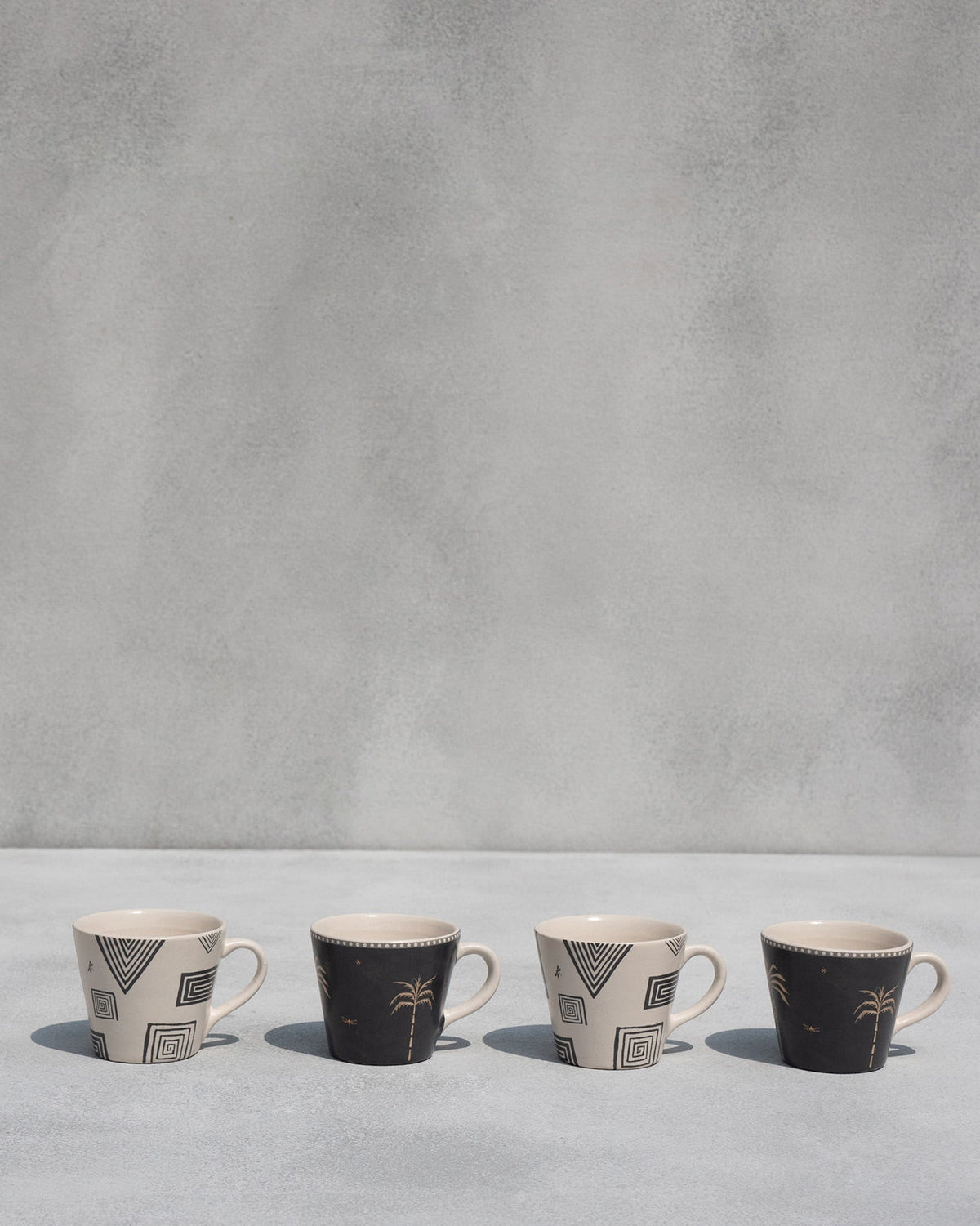 Four Serenity espresso mugs alternating geometric and palm tree prints.