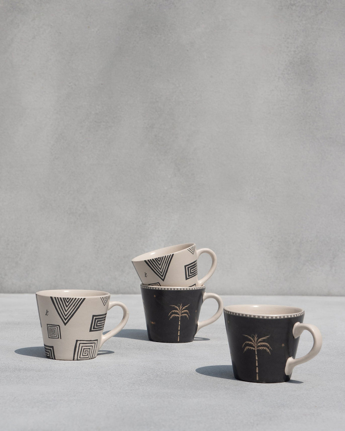Serenity espresso mugs arranged in geometric and black palm designs.