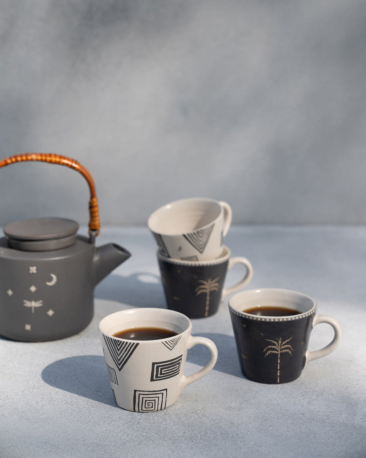 Serenity espresso mugs with coffee beside a matching teapot.