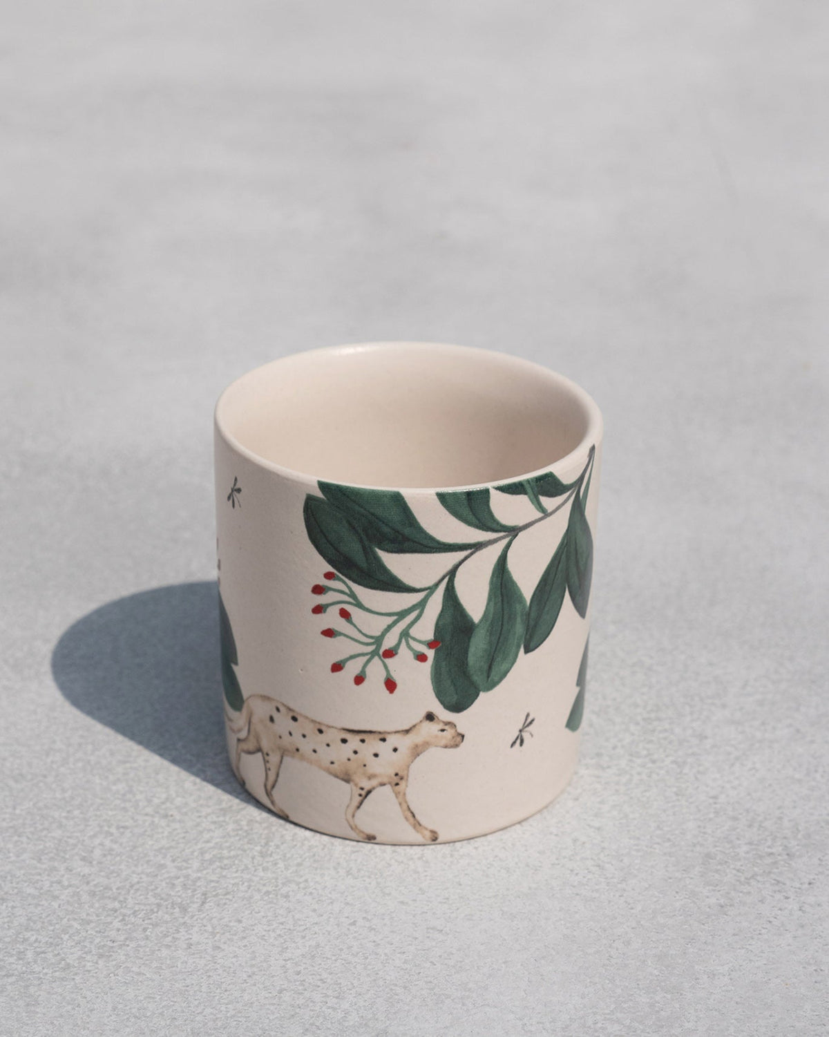 Zuri Straight Mug with a painted spotted animal and green leaves.