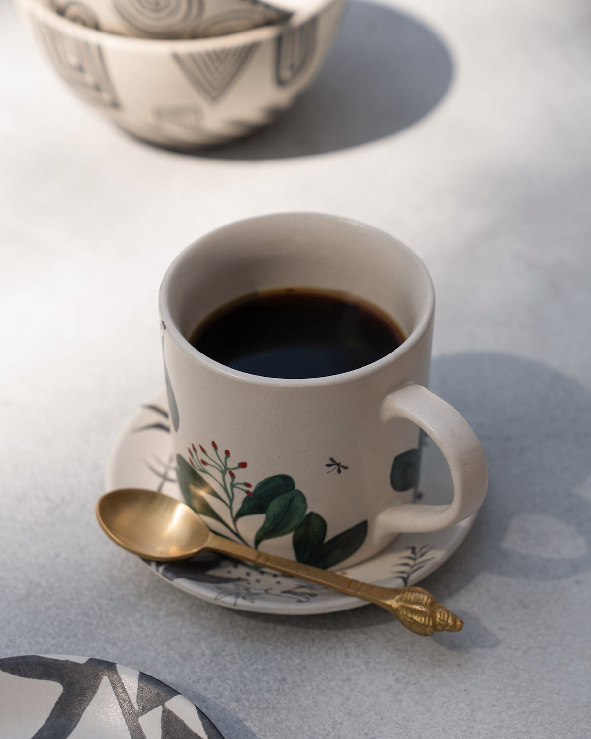 Zuri Straight Mug filled with coffee on a saucer.
