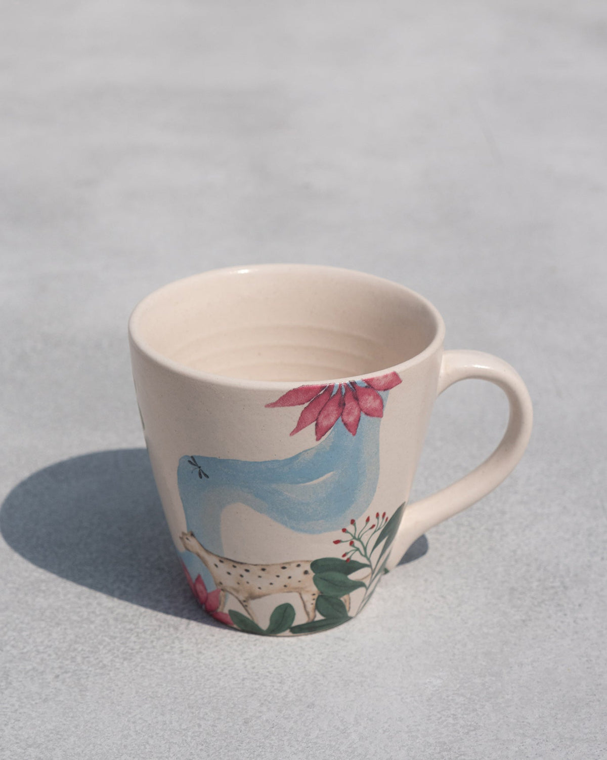 Three-quarter view of a Zanzibar Conical Mug with painted pink flowers and green leaves.