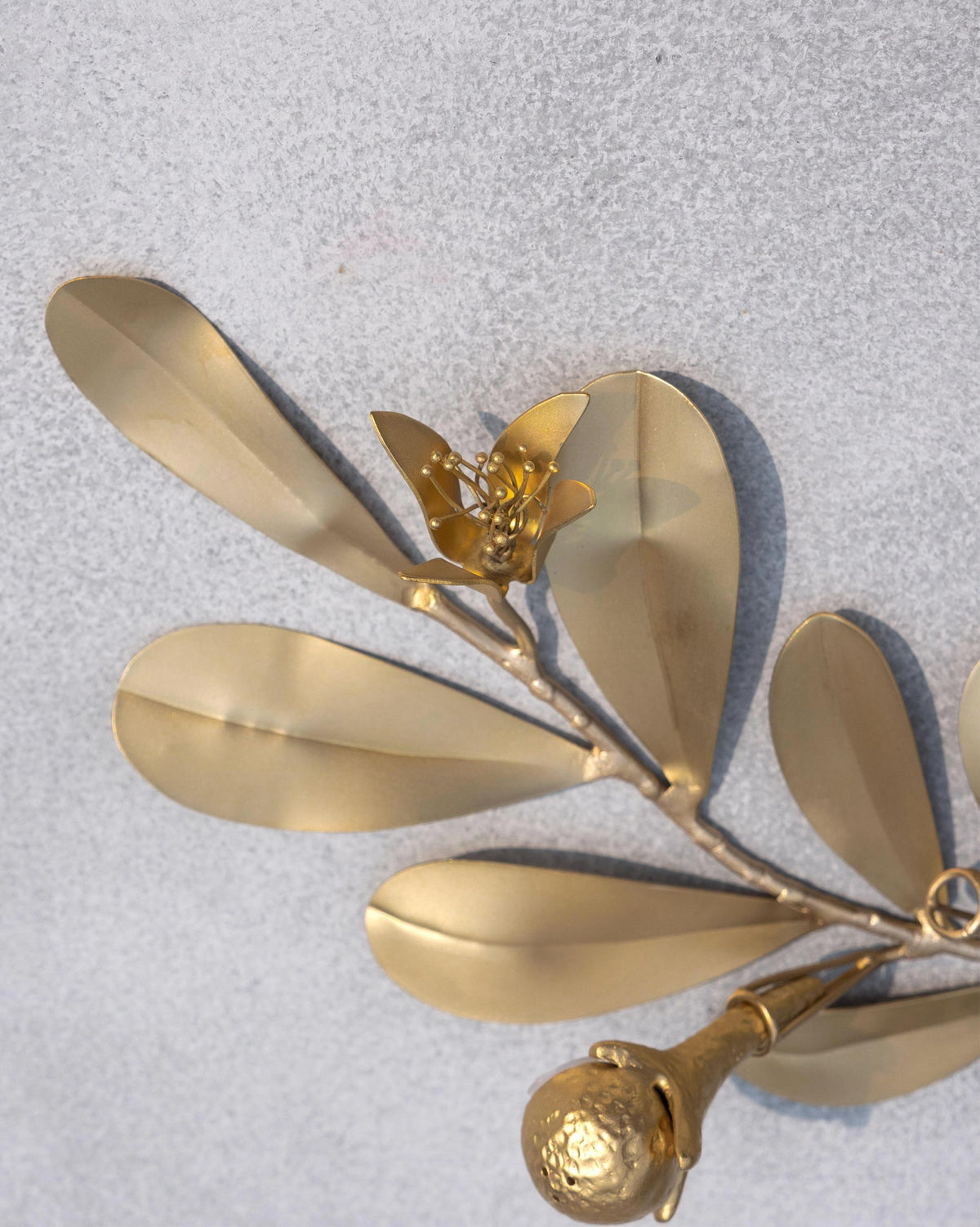 Close-up of a gold Clove holder showing leaves, a flower, and a clove bud.