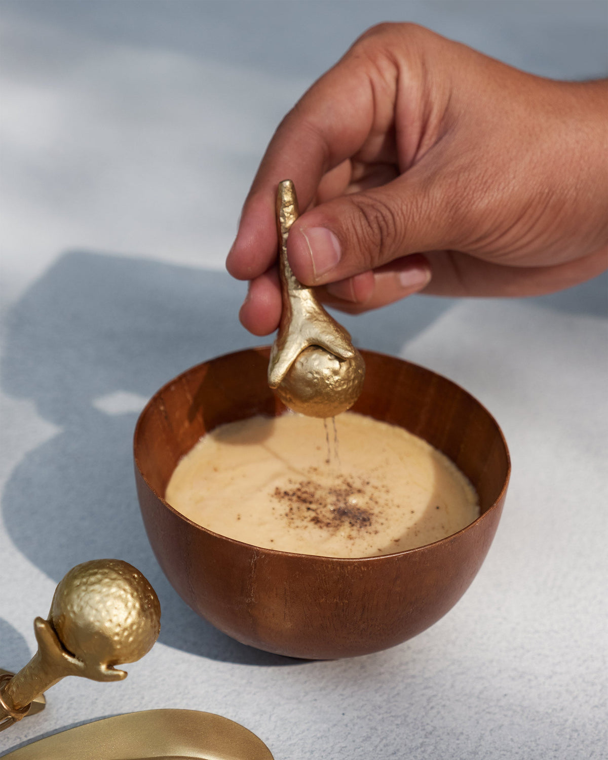 Gold Clove Salt and Pepper Shaker sprinkling spice into a dip bowl.