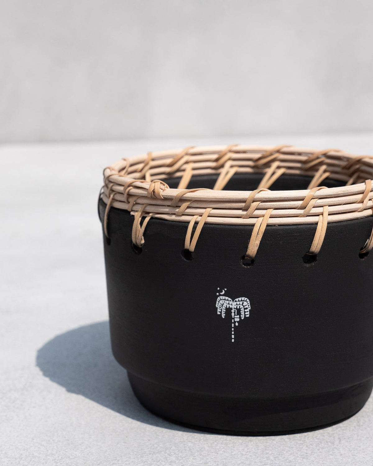 Close-up of a Zanzibar Planter showing its woven rattan rim and palm motif.
