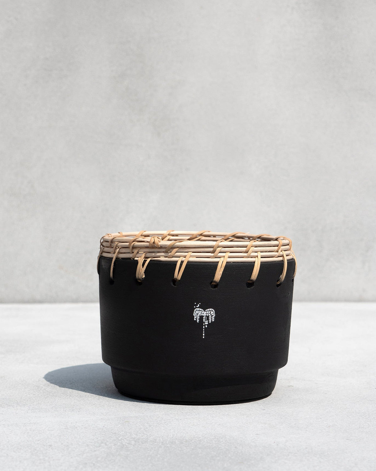 Black Zanzibar Planter with a rattan rim, shown straight on.