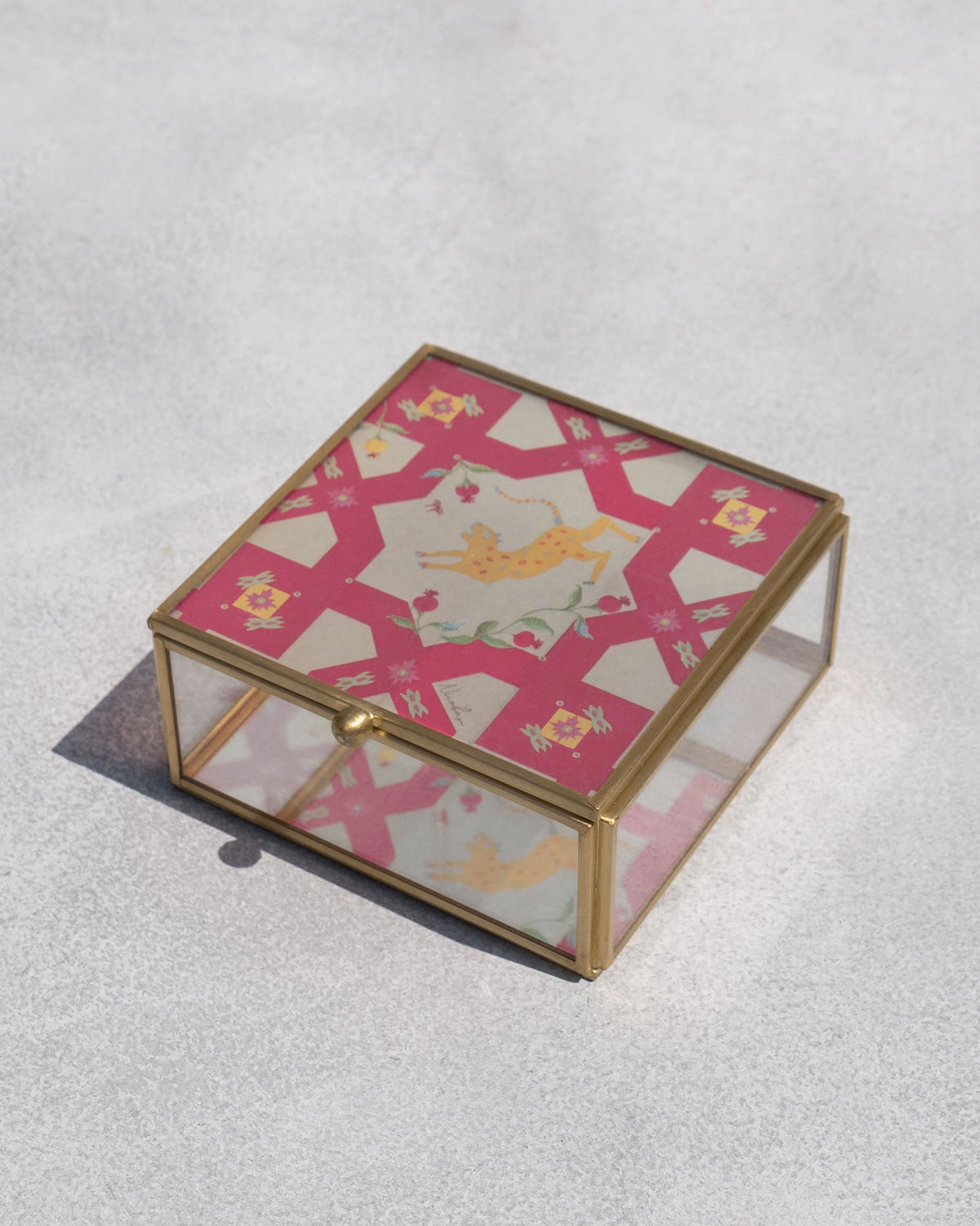 Closed Leopard Jewellery Box with a brass frame and glass sides, seen at an angle.