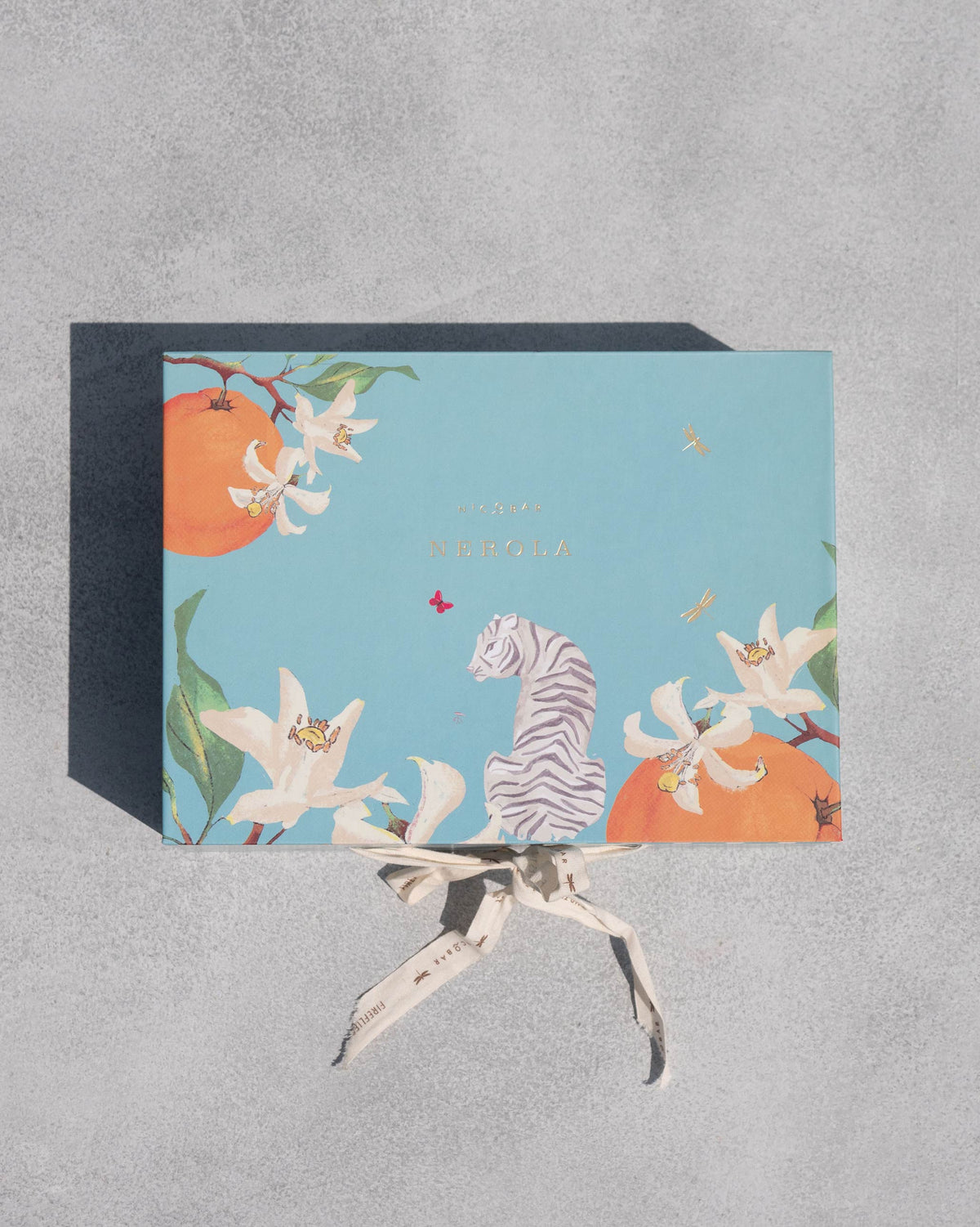 Closed Meraki Gift Set box in blue with oranges, lilies and a tiger, tied with a ribbon.