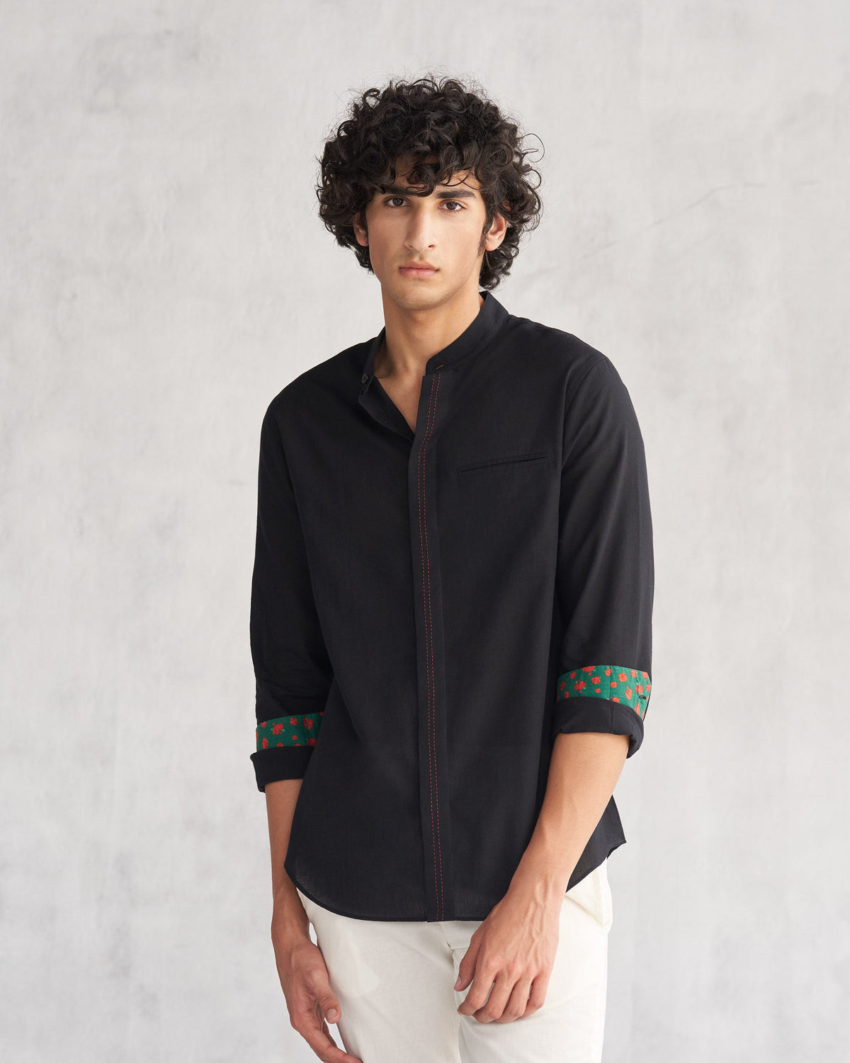 Person wearing a black Valley shirt with a red-stitched placket and printed cuff linings.