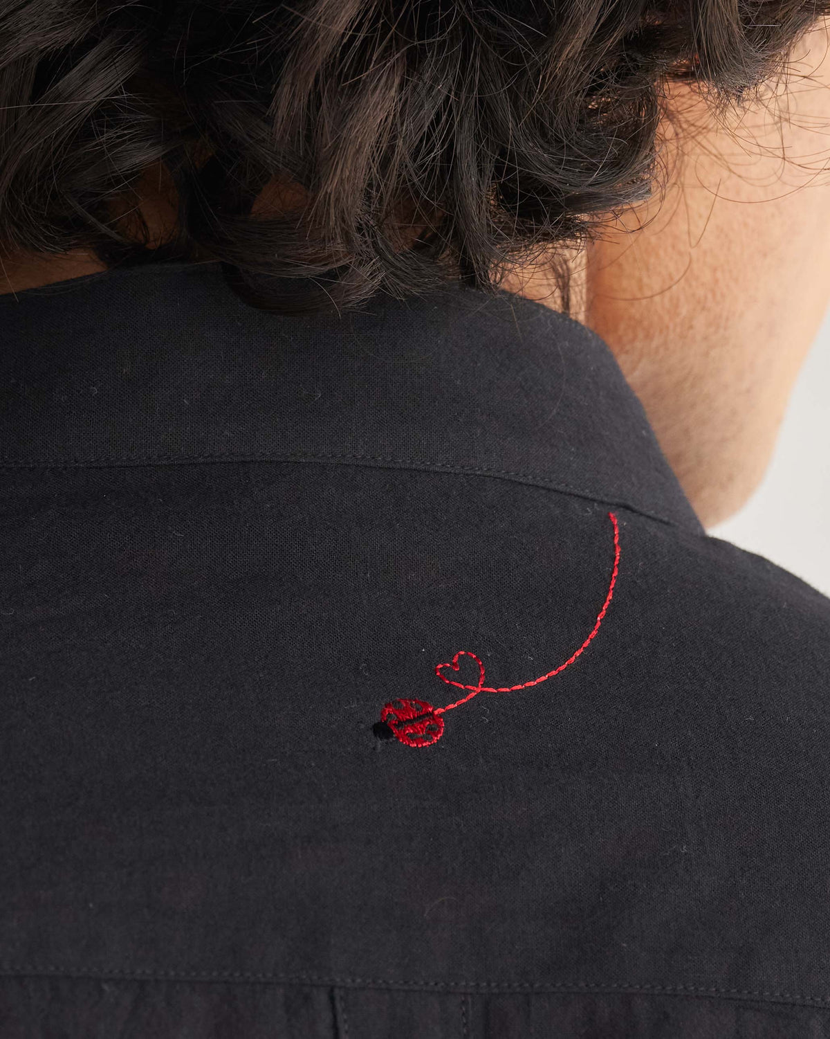 Close-up of a Valley shirt's upper back showing a red embroidered ladybug.