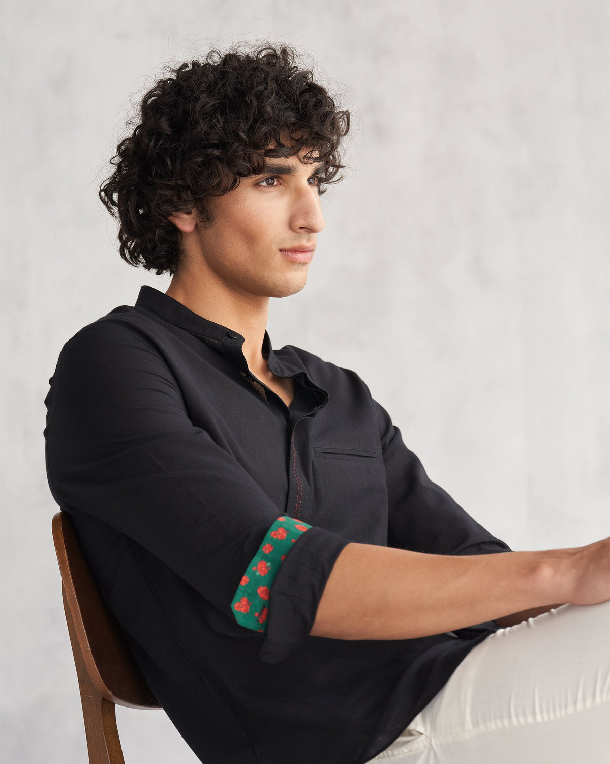 Side view of a black Valley shirt with a rolled printed cuff worn by a person.