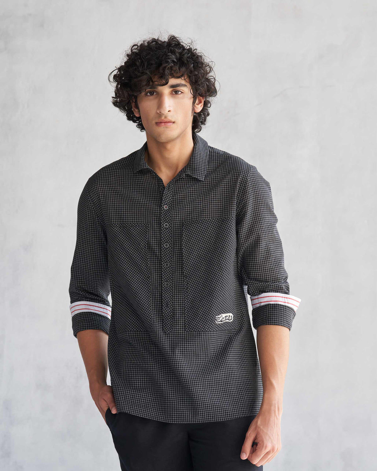 Person wearing the Big Pocket shirt, a black shirt with a fine white grid check and two chest pockets.