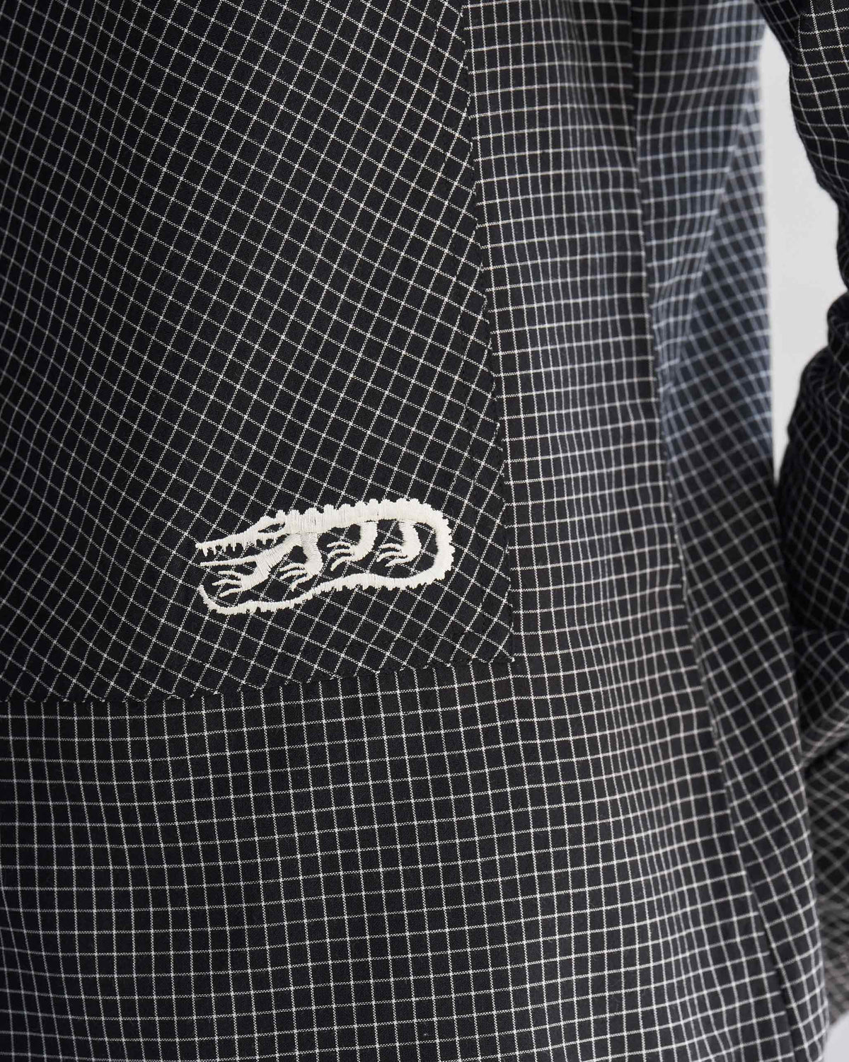 Close-up of the Big Pocket shirt grid check, with a small white embroidered badge.
