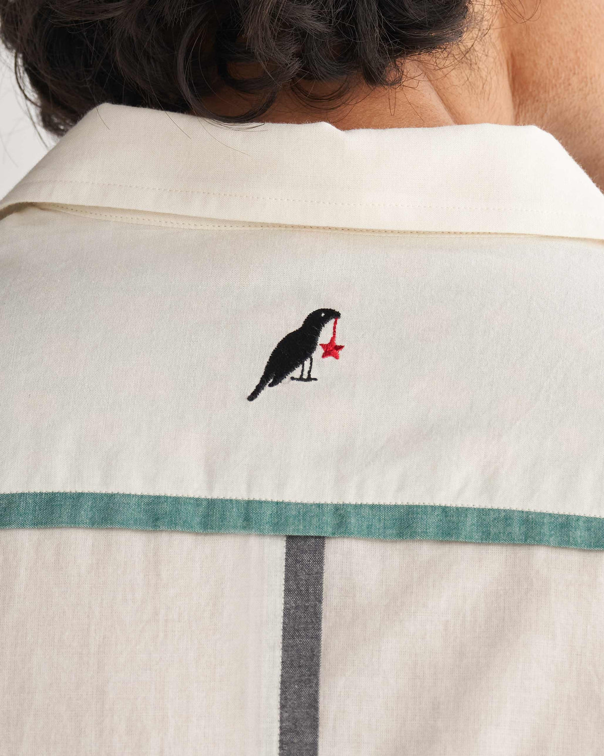 Close-up of the back yoke of an ivory Kangra Shirt showing a black bird with a red star.