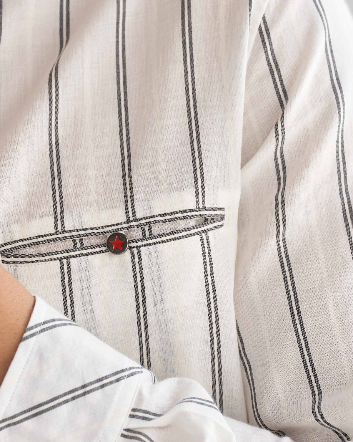 Close-up of the chest pocket on an ivory and black Pondicherry shirt, fastened with a red star button.