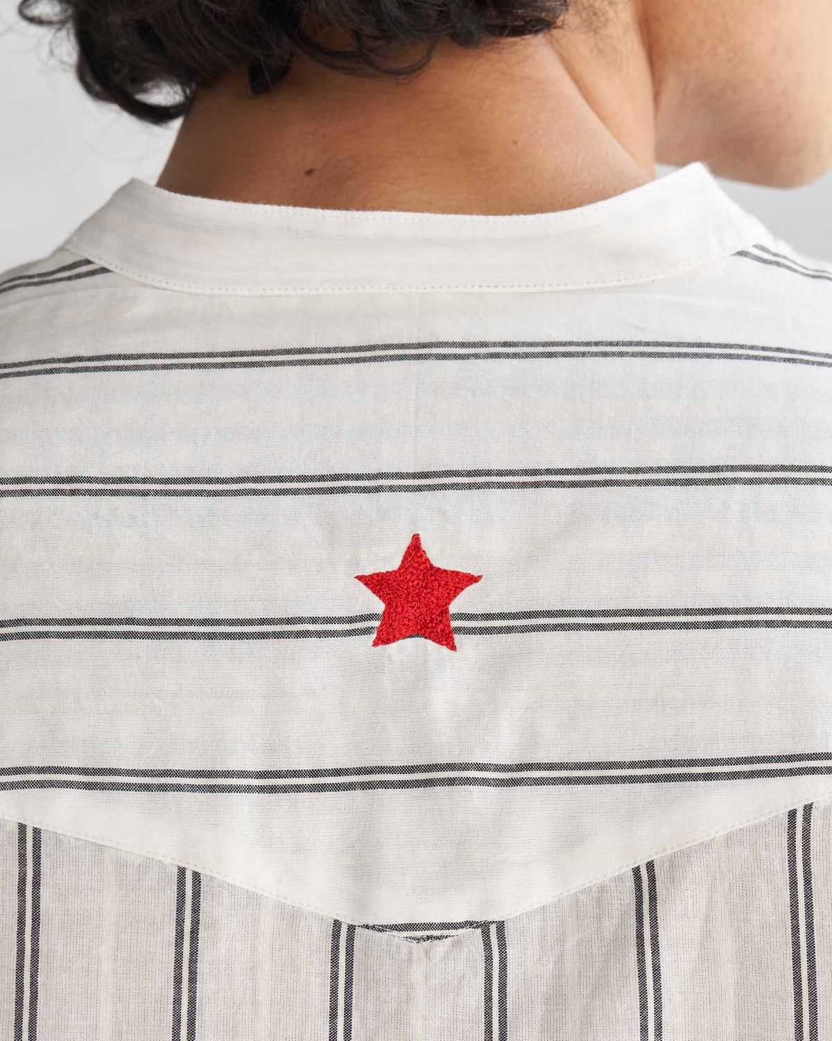 Close-up of the upper back of an ivory and black Pondicherry shirt showing a red star embroidery.