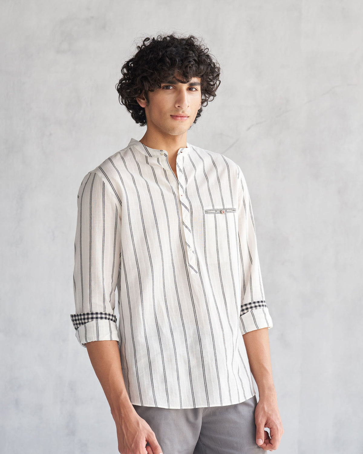 Person wearing an ivory and black Pondicherry shirt with the sleeves rolled to the forearm.