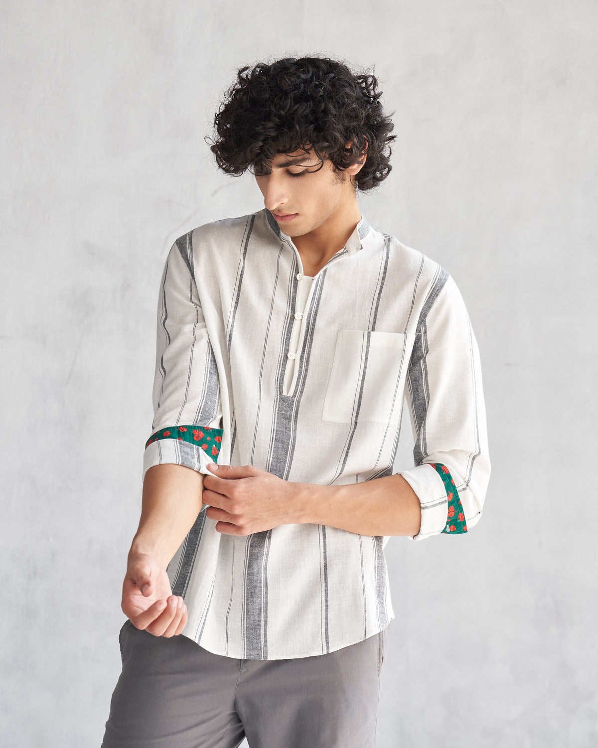 Person wearing an ivory Novac shirt with rolled sleeves and grey stripes.